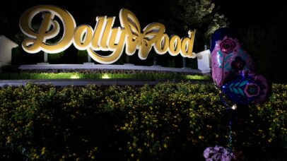 A placa do Dollywood, o parque temático fundado por Dolly Parton em 1961, está iluminada à noite em meio a algumas lembranças deixadas por fãs em agosto de 2026 em Pigeon Forge, Tennessee (Foto: Melissa Sue Gerrits/Getty Images)