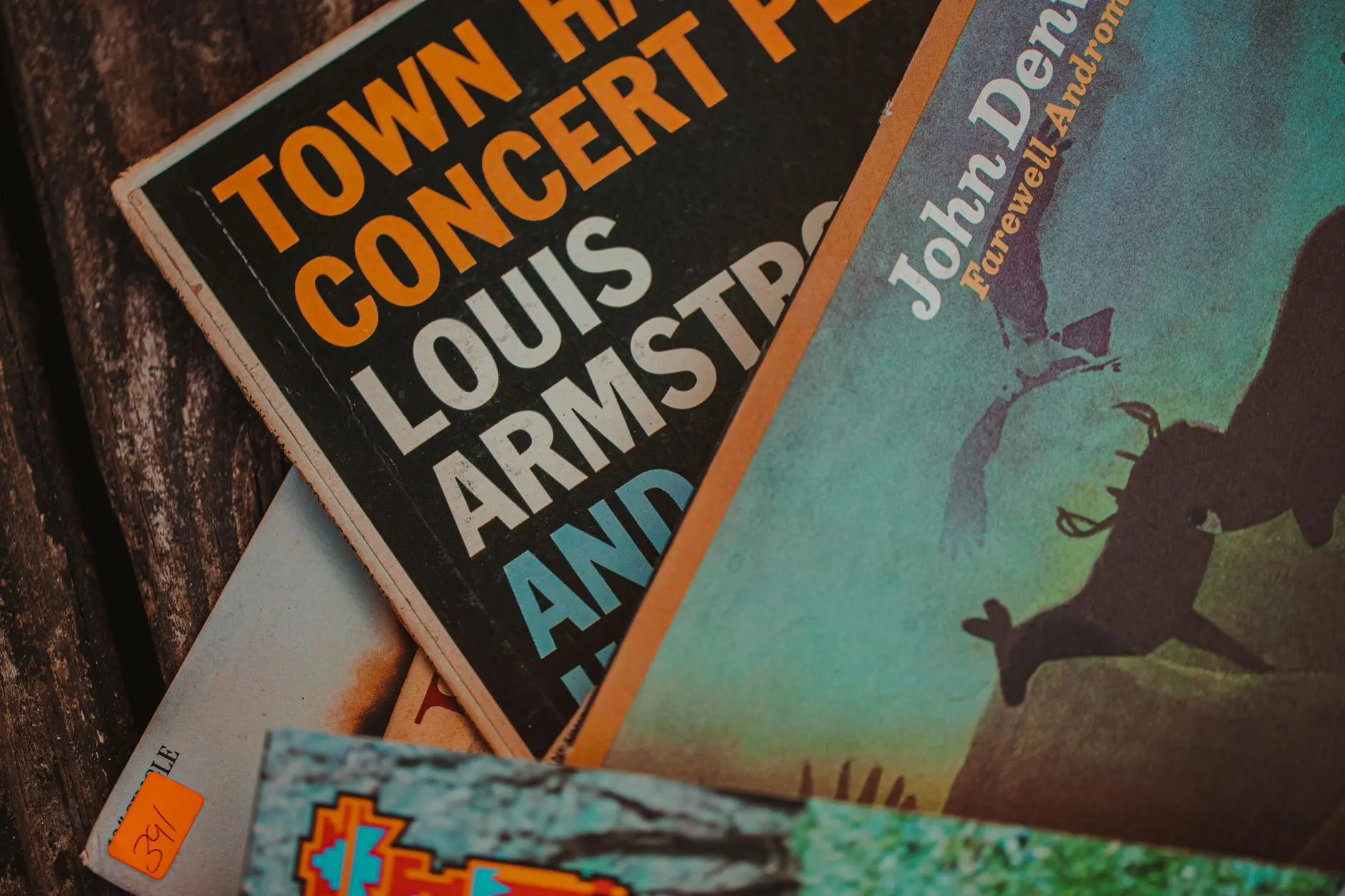 10 ganadores históricos del Latin Grammy 17 Primer plano de portadas de discos antiguos que muestran a John Denver y Louis Armstrong, en un entorno de Alabama.